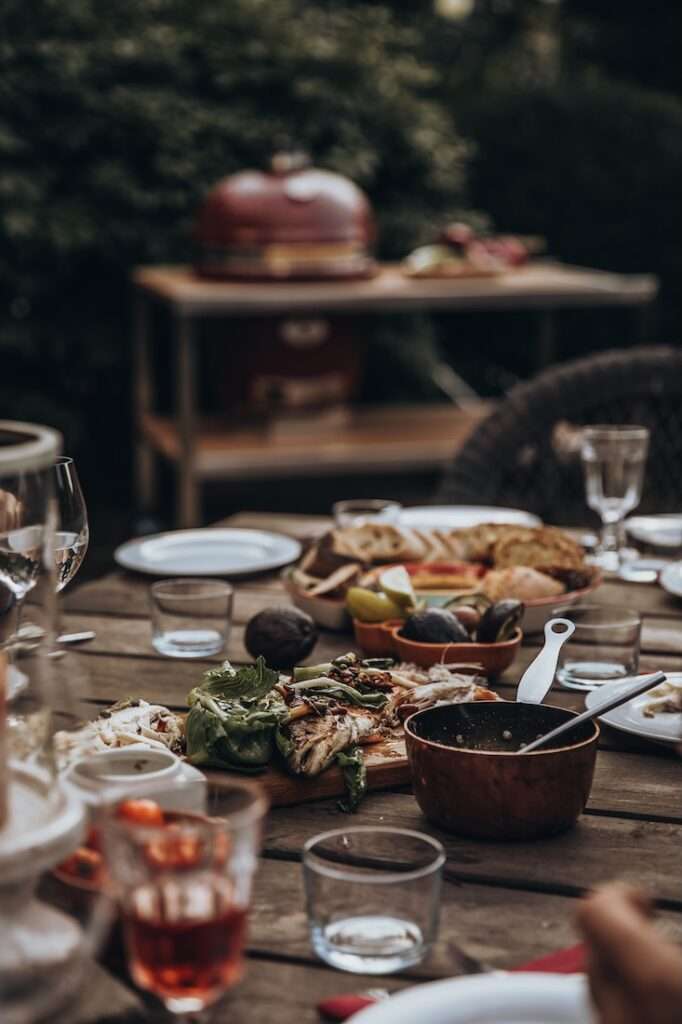 Monolith Kamado Grills 2 Monolith Kamado Keramikgrill in weinrot mit Esstisch im Vordergrund