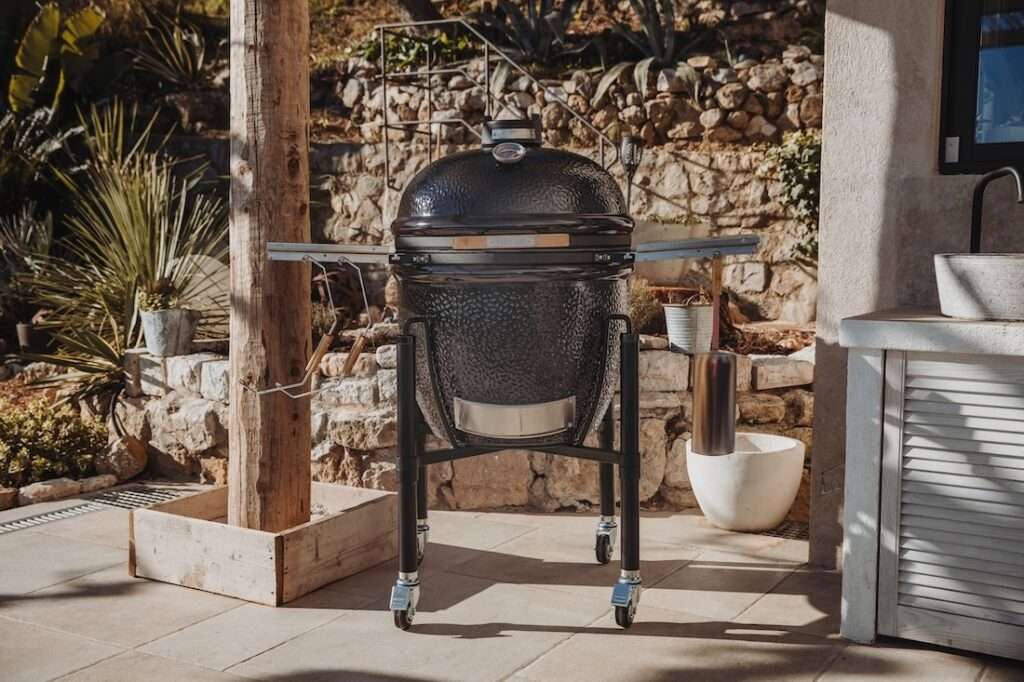 Schwarzer Keramikgrill auf Rädern in mediteranem Umfeld